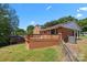 Backyard of a brick home featuring a spacious wooden deck, green lawn, and mature trees against a clear blue sky at 5301 Baker Dr, Charlotte, NC 28210