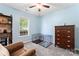 Relaxing bedroom with hardwood dresser, ceiling fan, plush chair and a neutral color scheme at 5927 Patricia Ryan Dr, Charlotte, NC 28216