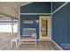 Close up of a welcoming porch with a yellow door, bench, and charming decor at 63 Frost Ln, Taylorsville, NC 28681