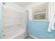 Bright bathroom with a shower-tub, blue tile accent, and window at 6325 Elmwood Cir, Charlotte, NC 28214