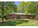 Charming single-story brick home with a well-maintained lawn and mature trees, offering a serene setting at 6325 Elmwood Cir, Charlotte, NC 28214