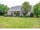 Beautiful backyard featuring a well-manicured lawn, mature trees, and a charming covered porch, ideal for outdoor relaxation at 7701 Gold Hill Rd, Rockwell, NC 28138