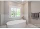 Bright bathroom with an oval soaking tub below a window with plantation shutters at 7701 Gold Hill Rd, Rockwell, NC 28138