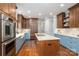 Spacious kitchen featuring custom cabinets, an island with cooktop, stainless appliances, and hardwood floors at 7701 Gold Hill Rd, Rockwell, NC 28138