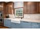 Charming kitchen features custom cabinets, farmhouse sink, granite countertops, and stainless steel appliances at 7701 Gold Hill Rd, Rockwell, NC 28138