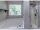 Clean bathroom featuring a tub, separate shower, and window, providing natural light at 8607 Cedardale Ridge Ct, Charlotte, NC 28269