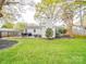 Backyard view features a deck with seating, a barbecue grill, mature trees, and lush landscaping at 901 Burnley Rd, Charlotte, NC 28210