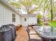 Wet backyard deck featuring a dining table, grill and seating outside of a charming brick house at 901 Burnley Rd, Charlotte, NC 28210
