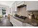 Close-up of the kitchen with a gas range, granite countertops, and white cabinets and decorative backsplash at 101 Cross Current Ln # 137, Belmont, NC 28012