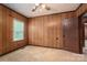 Bedroom with wood paneling, neutral carpet, a window for natural light, and an open doorway at 1501 Nc Hwy 73 Hwy, Iron Station, NC 28080
