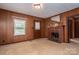 Living room with wood paneling, carpet, a brick fireplace, and ample natural light from a window at 1501 Nc Hwy 73 Hwy, Iron Station, NC 28080