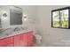 Bright bathroom featuring pink vanity, marble countertops, and a window with a serene outdoor view at 153 High Hills Dr, Mooresville, NC 28117