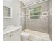 Bathroom featuring tile shower, patterned window, and neutral gray color scheme at 2218 W Fifth Ave, Gastonia, NC 28052