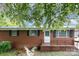 Charming brick home featuring a covered front porch and mature trees at 2218 W Fifth Ave, Gastonia, NC 28052