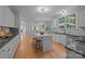 Open kitchen with island and stools, white cabinets, wood floors and stainless appliances at 263 Fernbrook Dr, Mooresville, NC 28117