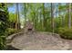 Outdoor stone patio featuring a cozy fireplace surrounded by lush greenery, perfect for relaxation at 263 Fernbrook Dr, Mooresville, NC 28117