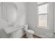 Clean and simple bathroom featuring a white pedestal sink, toilet, and window at 2821 Shamrock Dr, Charlotte, NC 28205