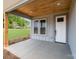 Covered porch features a wood ceiling, a white front door with glass inserts, and a view of the green lawn at 28655-A Nc Hwy 73 Hwy, Albemarle, NC 28001