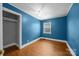 Vibrant blue bedroom with hardwood floors, ceiling fan, and large window, offering a comfortable retreat at 330 Clover St, Mooresville, NC 28115