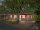 Quaint brick home with a well-kept lawn, mature tree, and inviting facade under evening light at 330 Clover St, Mooresville, NC 28115