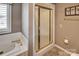 Bathroom featuring a tub, shower with gold trim and door, and a separate window providing natural light at 378 Shoreline Dr, New London, NC 28127