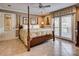 Well-lit main bedroom with a four-poster bed, tiled floors, and access to a balcony at 378 Shoreline Dr, New London, NC 28127