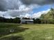 Exterior shot of a blue barn on a sunny, partly cloudy day, sitting amongst green grass at 4330 Goodman Lake Rd, Salisbury, NC 28146