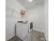 Convenient laundry room with modern washer and dryer, tile floors, and shelving at 5028 Whitemarsh Ct, Indian Land, SC 29720