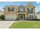 Inviting two-story brick home featuring a manicured lawn, a covered porch, and an attached garage at 5037 Nighthawk Dr, Fort Mill, SC 29707