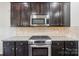 Close up of the kitchen with granite counters, stainless appliances, dark cabinets, and tile backsplash at 5037 Nighthawk Dr, Fort Mill, SC 29707
