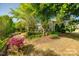 Lush backyard featuring mature trees, landscaped gardens, and a cozy patio perfect for outdoor relaxation and entertaining at 5050 Kinross Ln, Indian Land, SC 29707