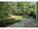 Lush backyard with a stone patio surrounded by mature trees at 6904 Mordred Ln, Charlotte, NC 28277