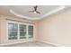 Bedroom featuring a tray ceiling, neutral carpet, and three large windows at 6904 Mordred Ln, Charlotte, NC 28277