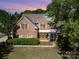 Charming two-story brick home with lush landscaping and covered front porch at 6904 Mordred Ln, Charlotte, NC 28277