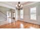 Dining room featuring hardwood floors, wainscoting, chandelier, and access to staircase and front entry at 6927 Ellington Farm Ln, Mint Hill, NC 28227