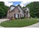 Side view of brick and stone home highlighting architectural details and landscaping, including mature trees at 6927 Ellington Farm Ln, Mint Hill, NC 28227