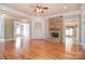 Open living room with stone fireplace, hardwood floors, built-in shelving, and ample natural light at 6927 Ellington Farm Ln, Mint Hill, NC 28227