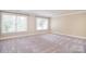 Large living room featuring two bright windows, neutral walls, and soft carpeting for a cozy feel at 6927 Ellington Farm Ln, Mint Hill, NC 28227