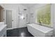 Bright bathroom with black floor tiles, walk-in shower and modern tub with a window view at 902 Hoke Trl, Cramerton, NC 28032