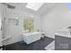 Bright bathroom with a skylight, modern tub, black floor tiles, and walk-in shower at 902 Hoke Trl, Cramerton, NC 28032