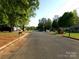 A wide shot of a tree-lined street with houses, lawns, and cars parked along the curb at 906 N 11Th St, Albemarle, NC 28001