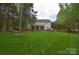 Sprawling backyard with a lush lawn, privacy fence, patio, sunroom, and mature trees at 9106 Dogwood Ridge Dr, Charlotte, NC 28227