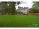 Large backyard with lush grass, mature trees, a wooden fence, and partial view of the house at 9106 Dogwood Ridge Dr, Charlotte, NC 28227