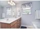 Bathroom with double vanity, floral valances, large mirror, and a window that allows natural light at 9106 Dogwood Ridge Dr, Charlotte, NC 28227