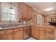 Kitchen featuring granite countertops and wooden cabinetry with stainless steel dishwasher and sink under the window at 9106 Dogwood Ridge Dr, Charlotte, NC 28227