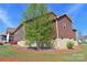 Side view of home with brown siding, a tree, green grass, and a blue sky at 164 Castle Pines Ln, Statesville, NC 28625
