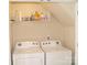 Efficient laundry room with washer and dryer, complemented by overhead storage shelves at 1960 Aston Mill Pl, Charlotte, NC 28273