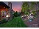 Landscaped backyard with a covered patio, stone fireplace, and manicured lawn at 2002 Thurston Dr, Indian Trail, NC 28079