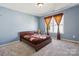 This bedroom is painted blue with a bed, grey carpet, window and brown curtains at 221 Sycamore Creek Rd, Fort Mill, SC 29708
