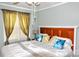Well-lit bedroom with a wood headboard, stylish pillows, and golden curtains at 2929 Matoka Trl, Matthews, NC 28104